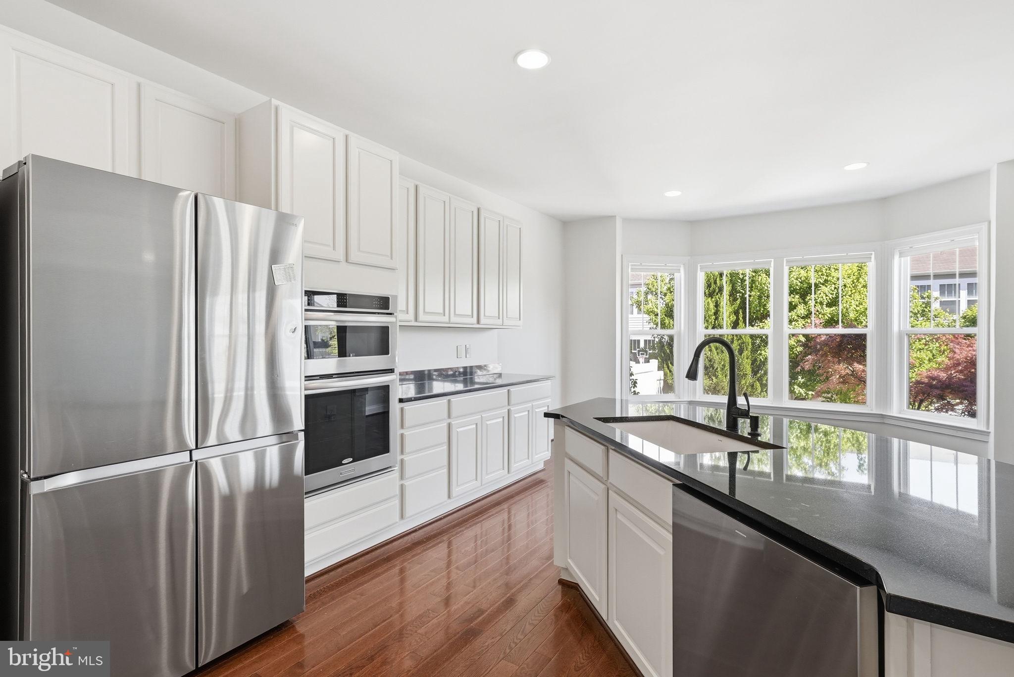 42330 Christophers View Terrace Ashburn, VA 20148 - Photo 11 of 46 a kitchen with kitchen island granite countertop white cabinets and stainless steel appliances