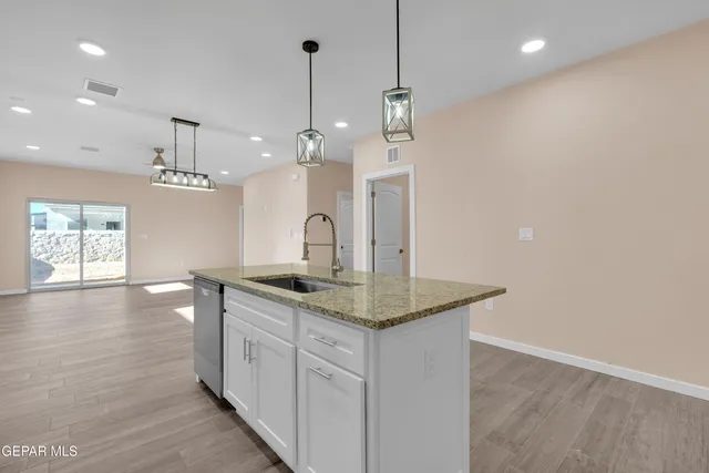 a kitchen with stainless steel appliances granite countertop a sink a window and wooden floor