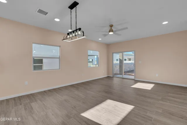 a view of an empty room with window and wooden floor