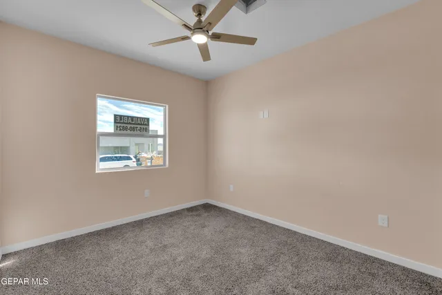 an empty room with a window and a fan