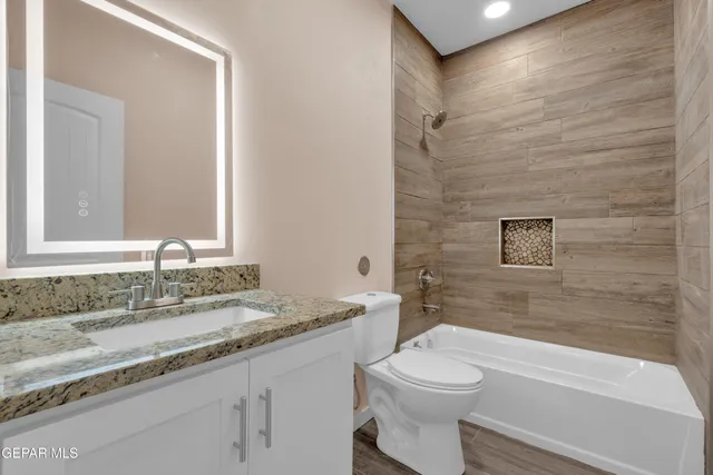 a bathroom with a granite countertop sink a toilet and bathtub