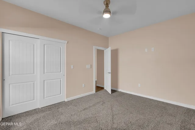 a view of an empty room and chandelier fan