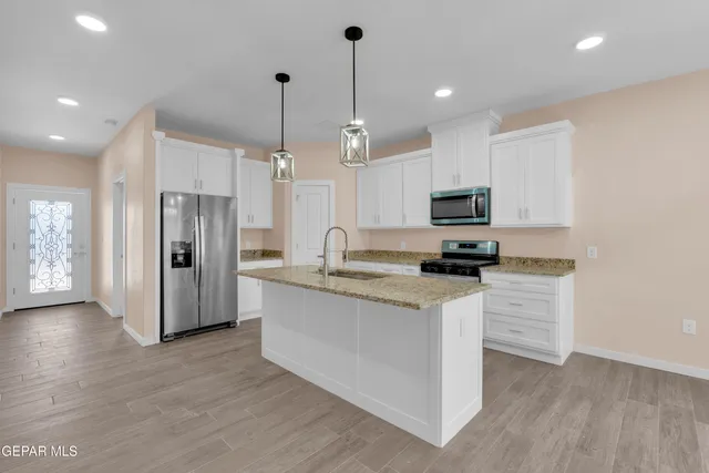 a kitchen with stainless steel appliances granite countertop a refrigerator a stove a sink dishwasher and a oven with wooden floor