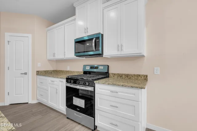 a kitchen with white cabinets and appliances