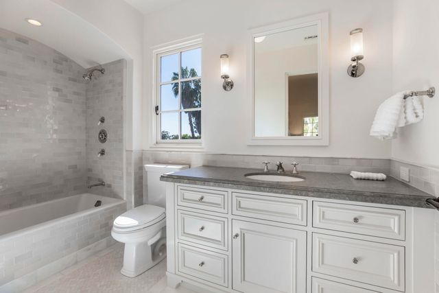 a bathroom with a granite countertop sink a toilet mirror and bathtub