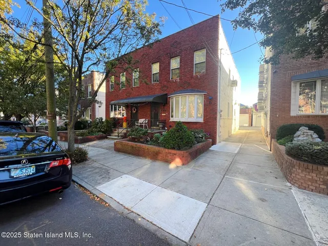 a view of a brick house with many windows and cars parked in front of a house