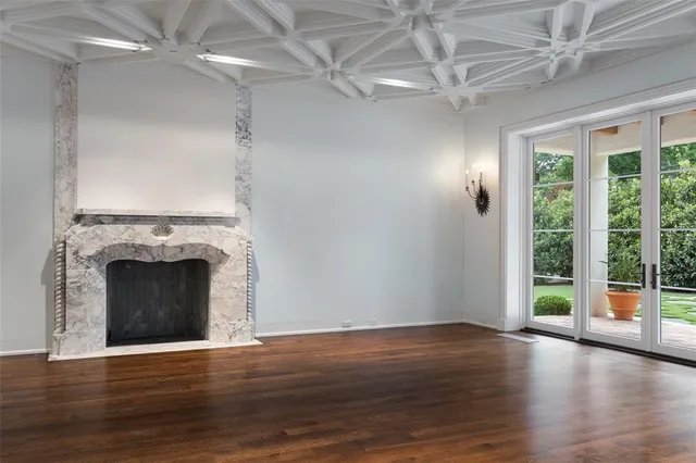 a view of an empty room with wooden floor fireplace and a window