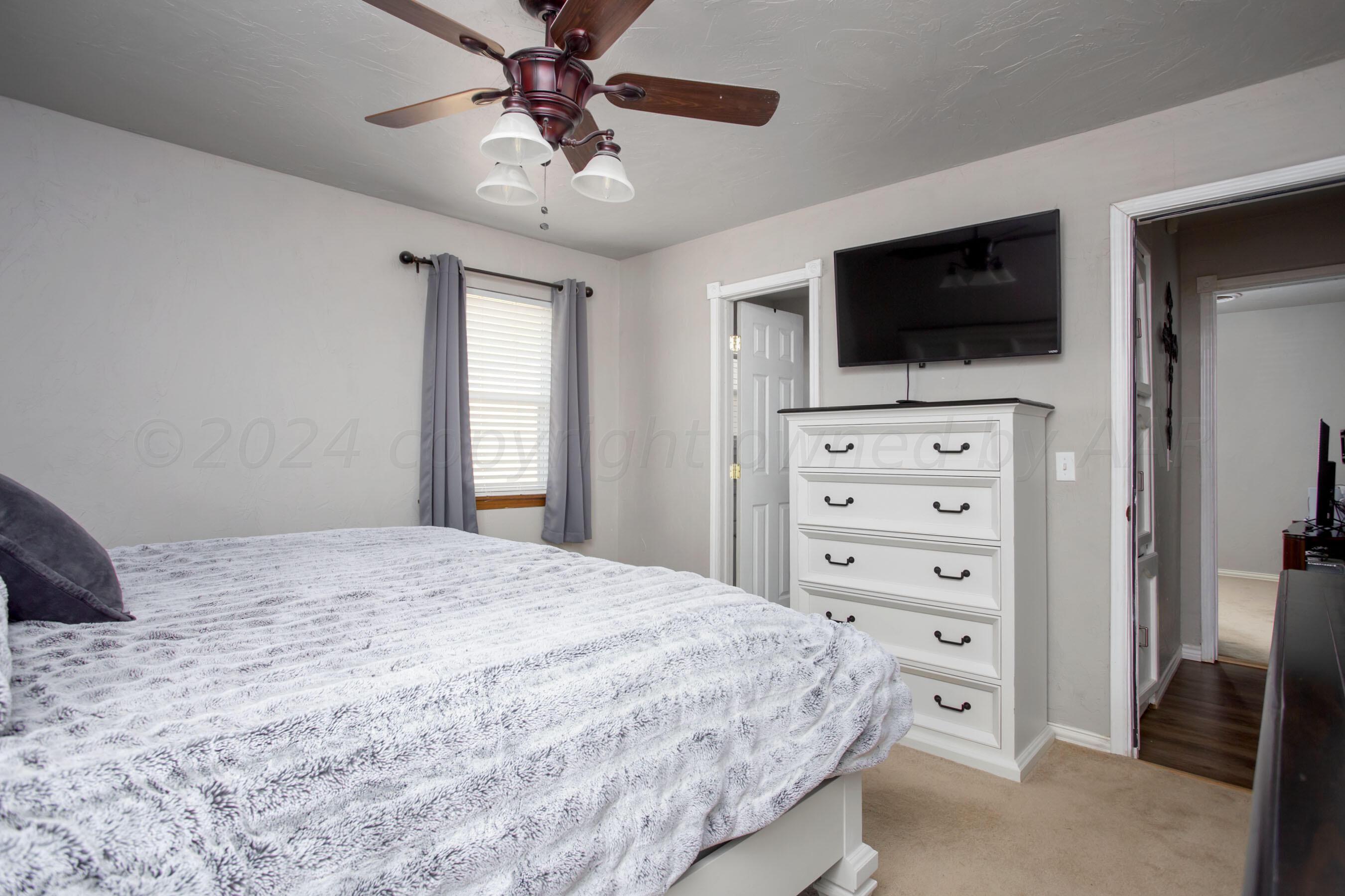 8122 Santa Fe Trail Amarillo, TX 79110 - Photo 16 of 23 a bedroom with a bed a flat screen tv and chandelier