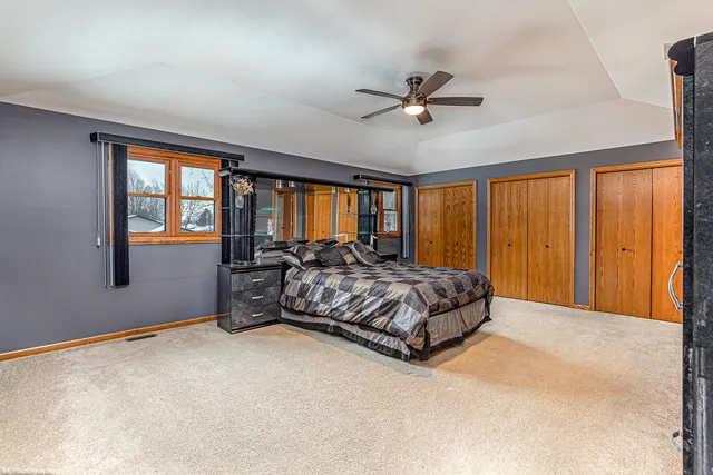 a bedroom with a large bed and windows