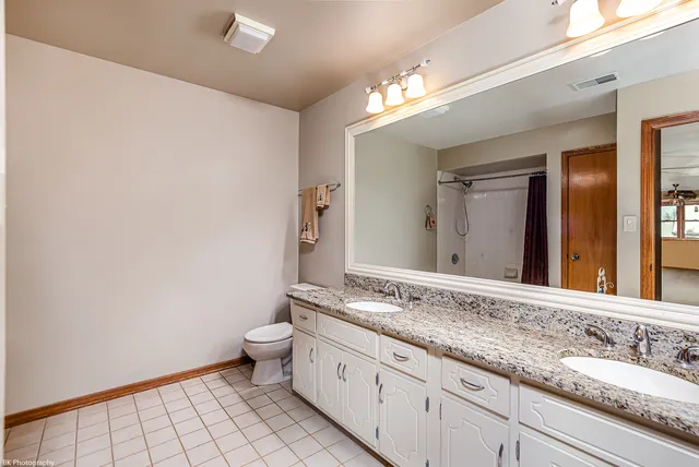 a bathroom with a granite countertop sink a toilet and a large mirror