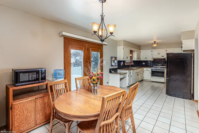 a dining room with stainless steel appliances granite countertop a dining table chairs refrigerator and cabinets