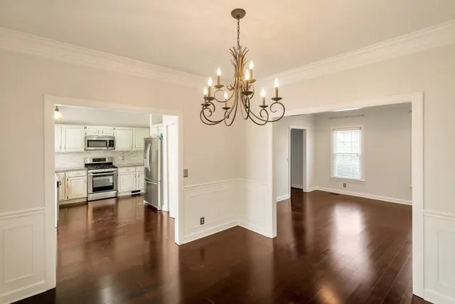 a view of a hallway with wooden floor and a chandelier