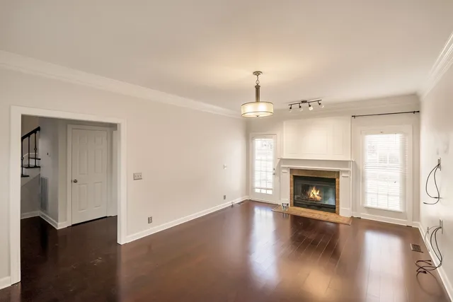 a view of an empty room with wooden floor fireplace and a window
