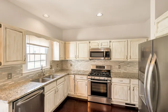 a kitchen with stainless steel appliances granite countertop a sink stove and refrigerator