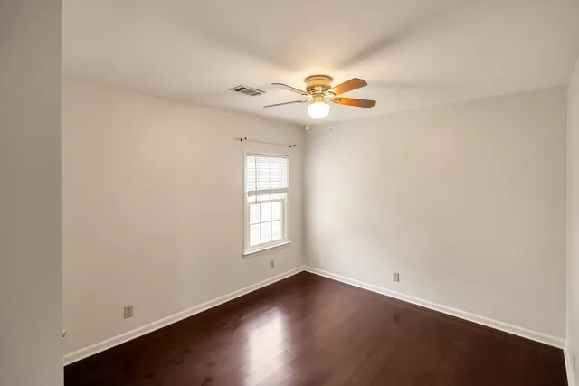 an empty room with windows and chandelier fan