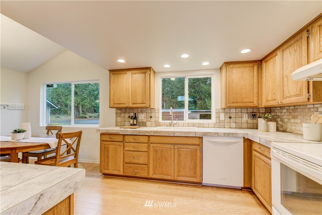 3327 Walsh Road Snohomish, WA 98290 - Photo 8 of 37 a kitchen with stainless steel appliances granite countertop a stove top oven a sink dishwasher a dining table and chairs with wooden floor