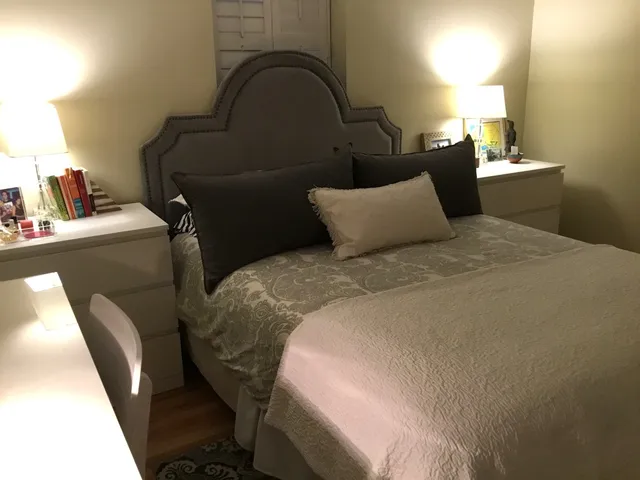 a bed sitting in a bedroom next to a lamp next to a window