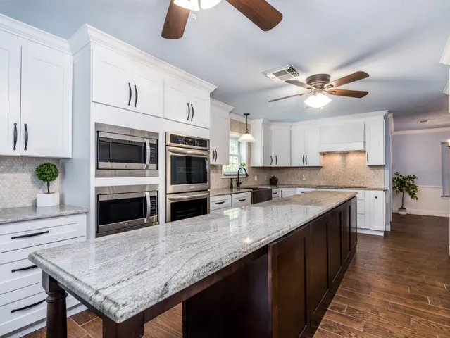 a kitchen with stainless steel appliances granite countertop a stove top oven a sink dishwasher and microwave with wooden floor