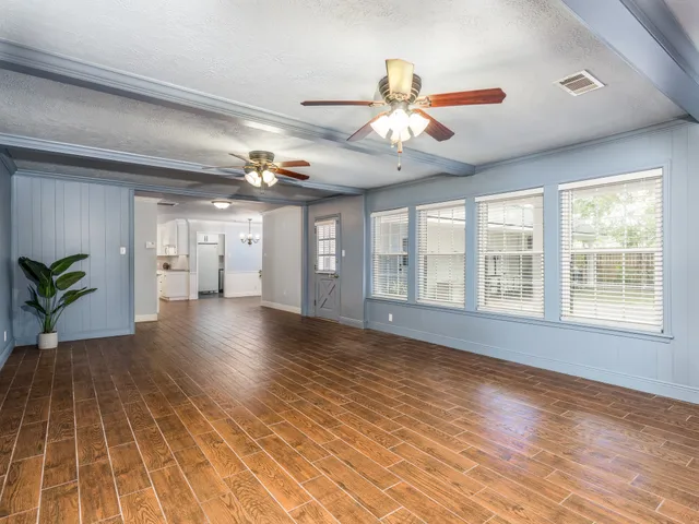 a view of an empty room with window and wooden floor