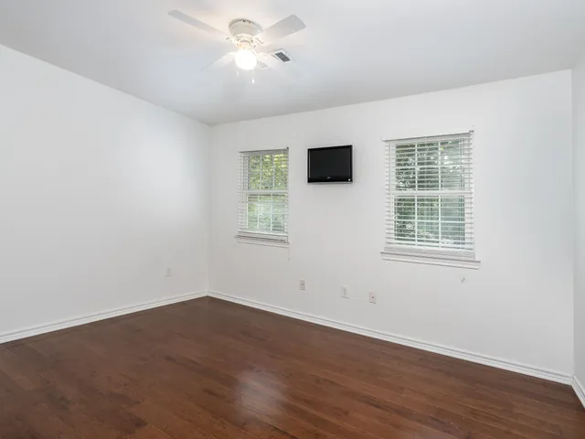 a view of an empty room with a window and wooden floor