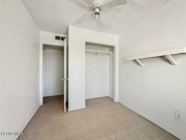 an empty room with a ceiling fan and a window