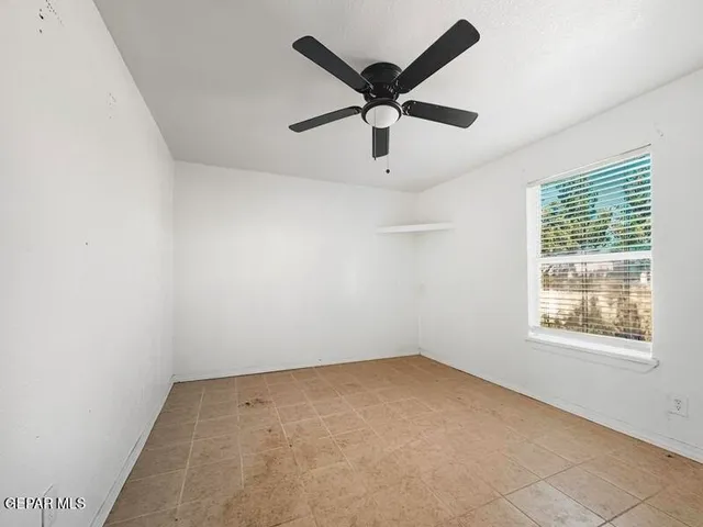 an empty room with a window and a fan