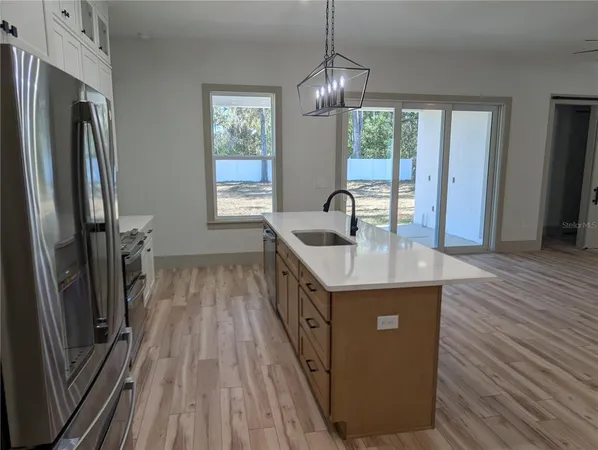a kitchen with sink a refrigerator and wooden floor
