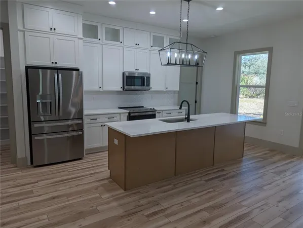 a kitchen with stainless steel appliances granite countertop a sink a stove a refrigerator and cabinets