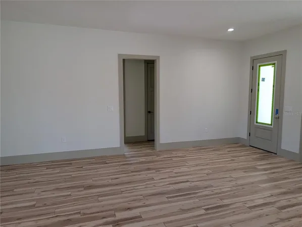 a view of an empty room with wooden floor and a window