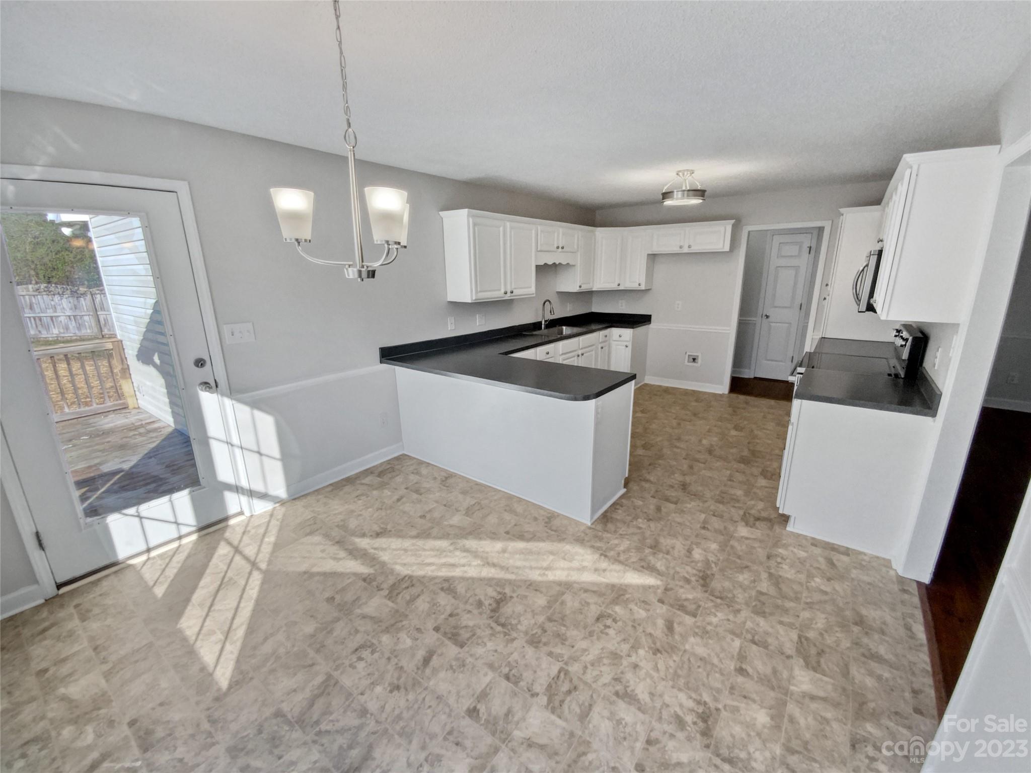 3415 Morgan Mill Road Monroe, NC 28110 - Photo 8 of 18 a large white kitchen with a sink a stove a refrigerator and a dining table with wooden floor