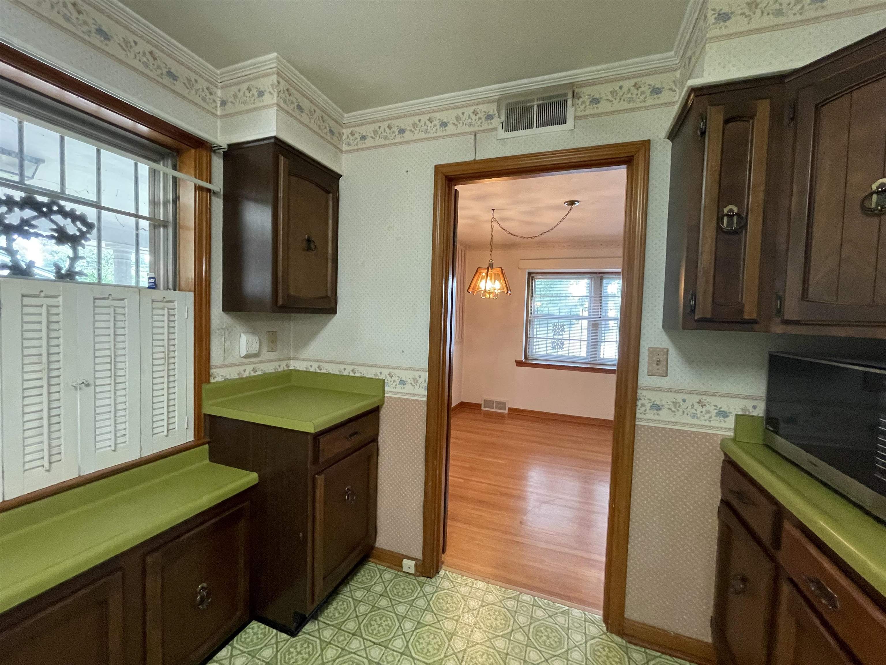 4857 Millbranch Road Memphis, TN 38116 - Photo 13 of 31 Kitchen with dark brown cabinets, crown molding, and light hardwood / wood-style floors