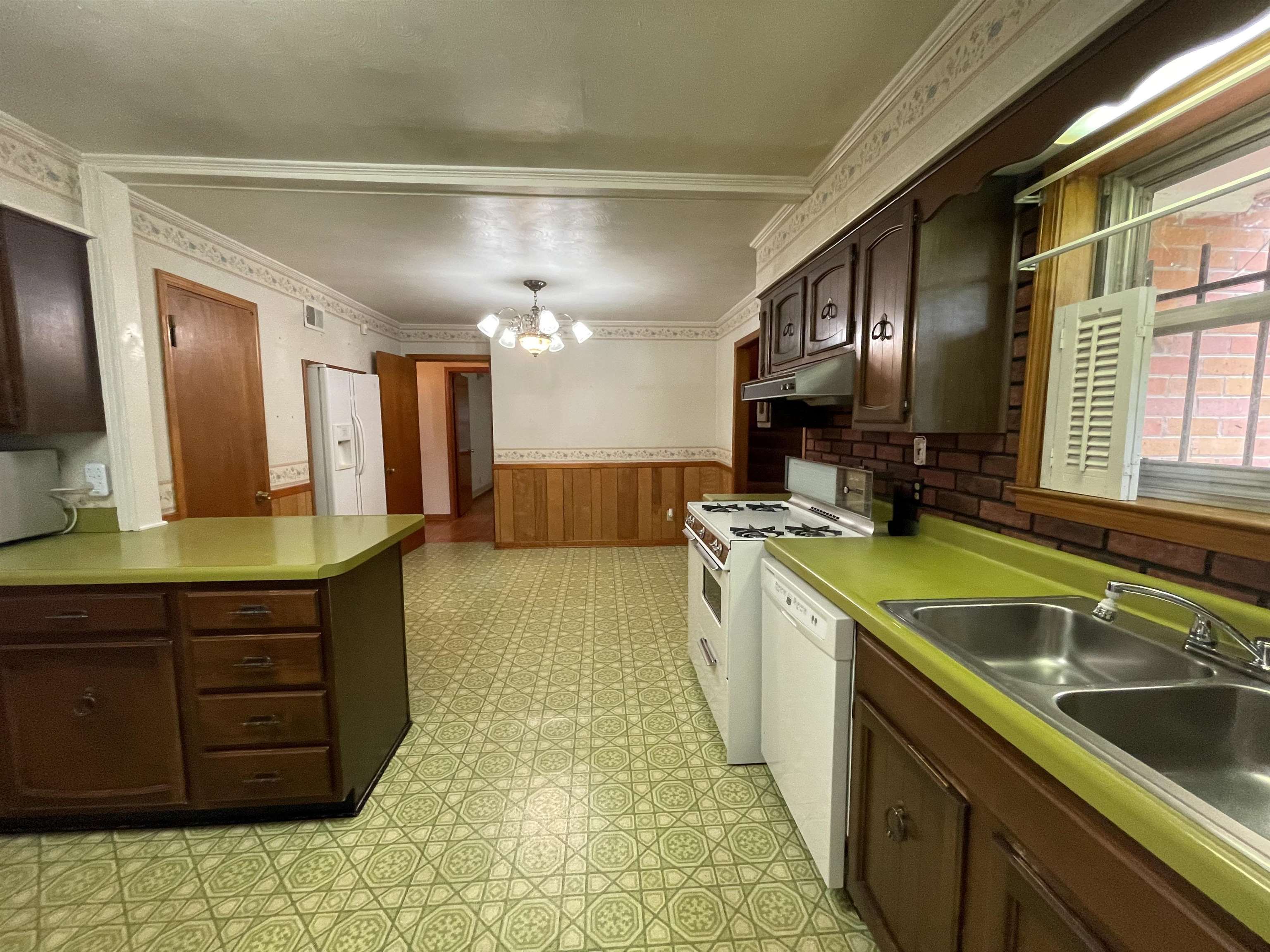 4857 Millbranch Road Memphis, TN 38116 - Photo 14 of 31 Kitchen featuring dark brown cabinetry, crown molding, light tile patterned flooring, and white appliances