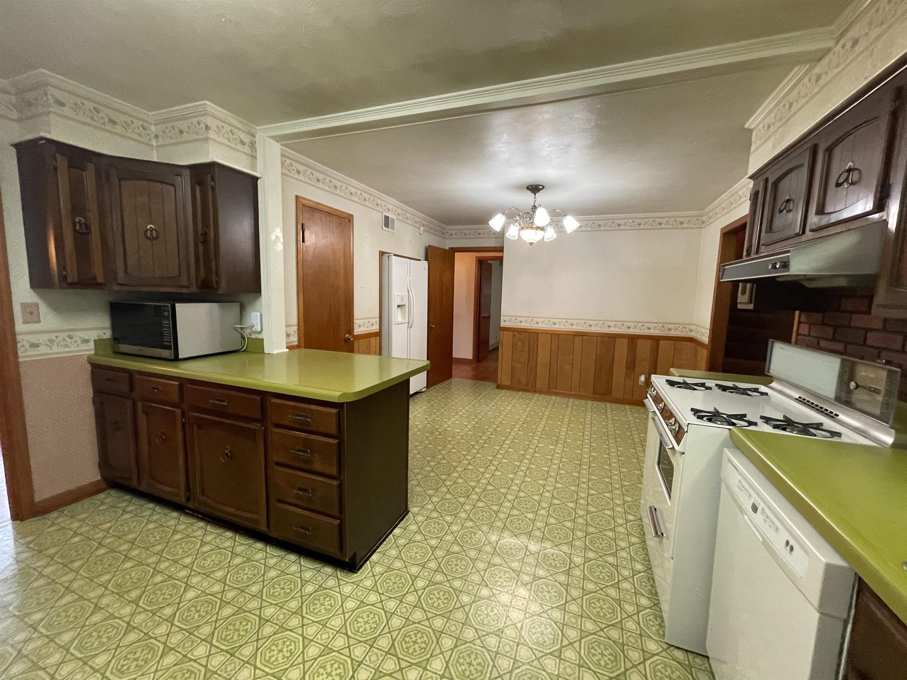 4857 Millbranch Road Memphis, TN 38116 - Photo 16 of 31 Kitchen featuring light tile patterned flooring, an inviting chandelier, crown molding, and white appliances