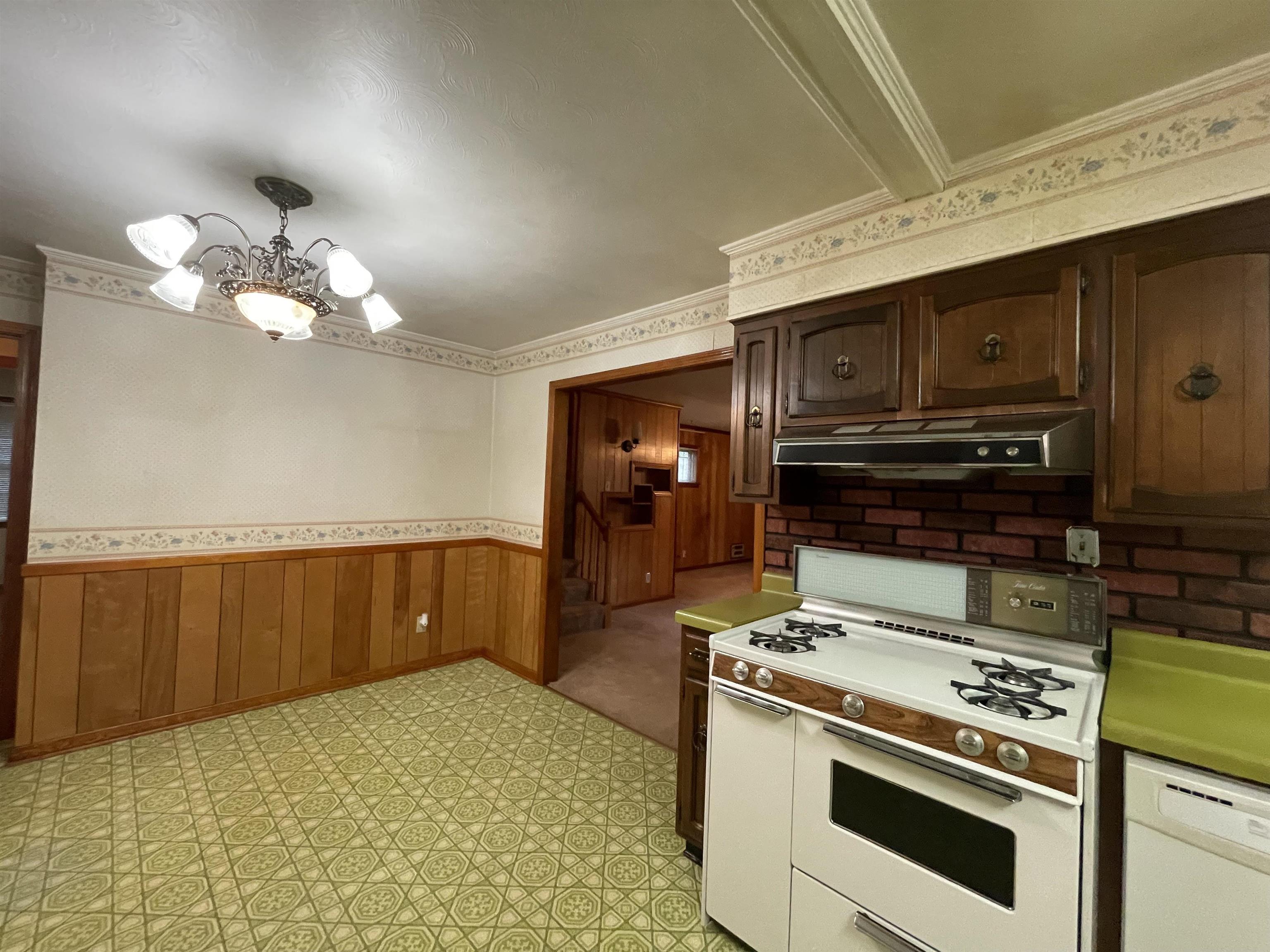 4857 Millbranch Road Memphis, TN 38116 - Photo 18 of 31 Kitchen with a notable chandelier, crown molding, white appliances, light tile patterned floors, and range hood
