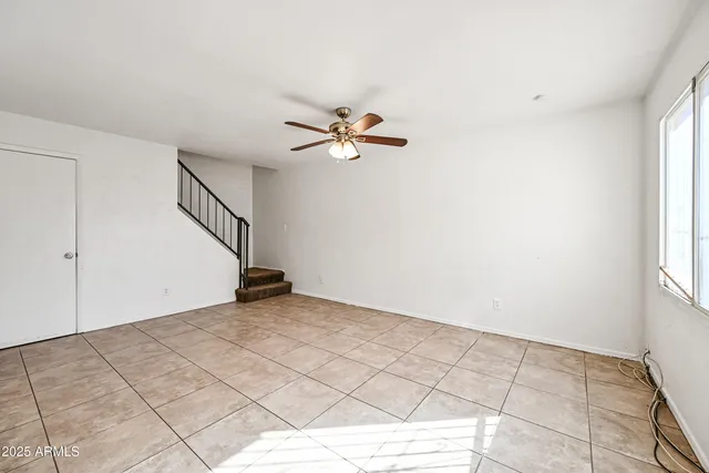 a view of an empty room and a ceiling fan and window