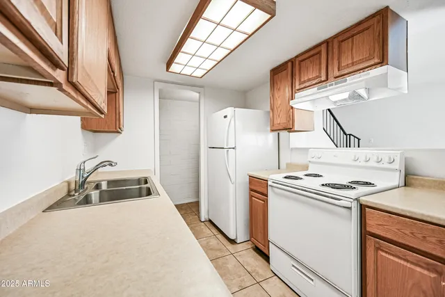 a kitchen that has a sink a stove and a refrigerator