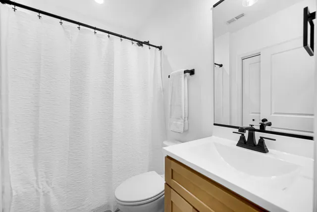 a bathroom with a sink a toilet a mirror and shower curtain