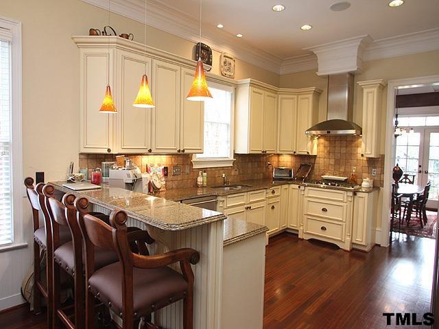 2105 Cowper Drive Raleigh, NC 27608 - Photo 7 of 25 a kitchen with stainless steel appliances granite countertop a stove a refrigerator a sink a dining table and chairs with wooden floor