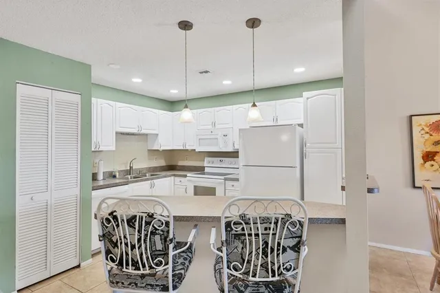 a kitchen with stainless steel appliances kitchen island granite countertop a table chairs and a refrigerator
