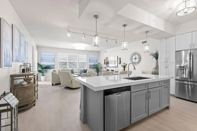 a kitchen with a sink a counter top space and living room view
