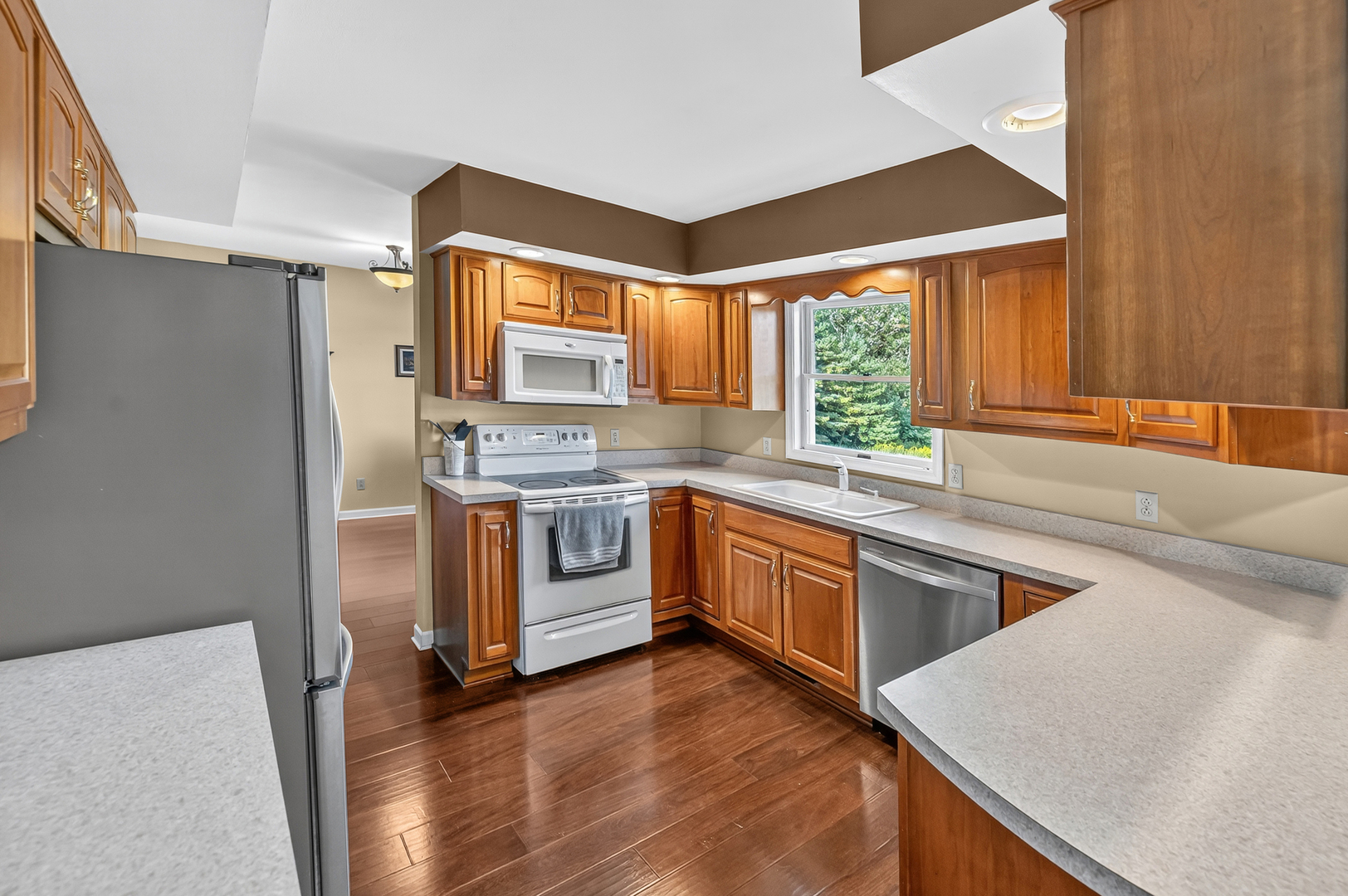 4454 North Prairie View Road Argenta, IL 62501 - Photo 12 of 45 a kitchen with stainless steel appliances granite countertop a refrigerator a sink dishwasher a stove and white countertops with wooden floor