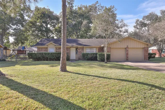 a view of a house with a yard and large tree