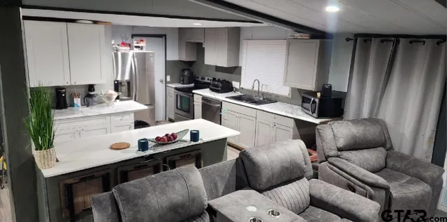 a work place with stainless steel appliances kitchen island granite countertop furniture and a view of kitchen