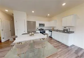 a large white kitchen with kitchen island a sink stainless steel appliances and cabinets