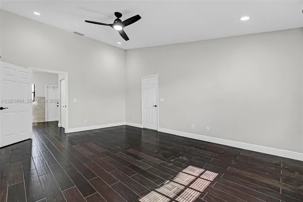 an empty room with wooden floor and ceiling fan