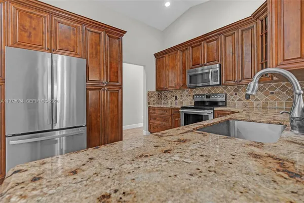 a kitchen with stainless steel appliances granite countertop a refrigerator stove and a sink