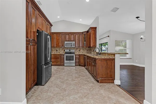a kitchen with stainless steel appliances granite countertop a stove top oven a refrigerator and a sink