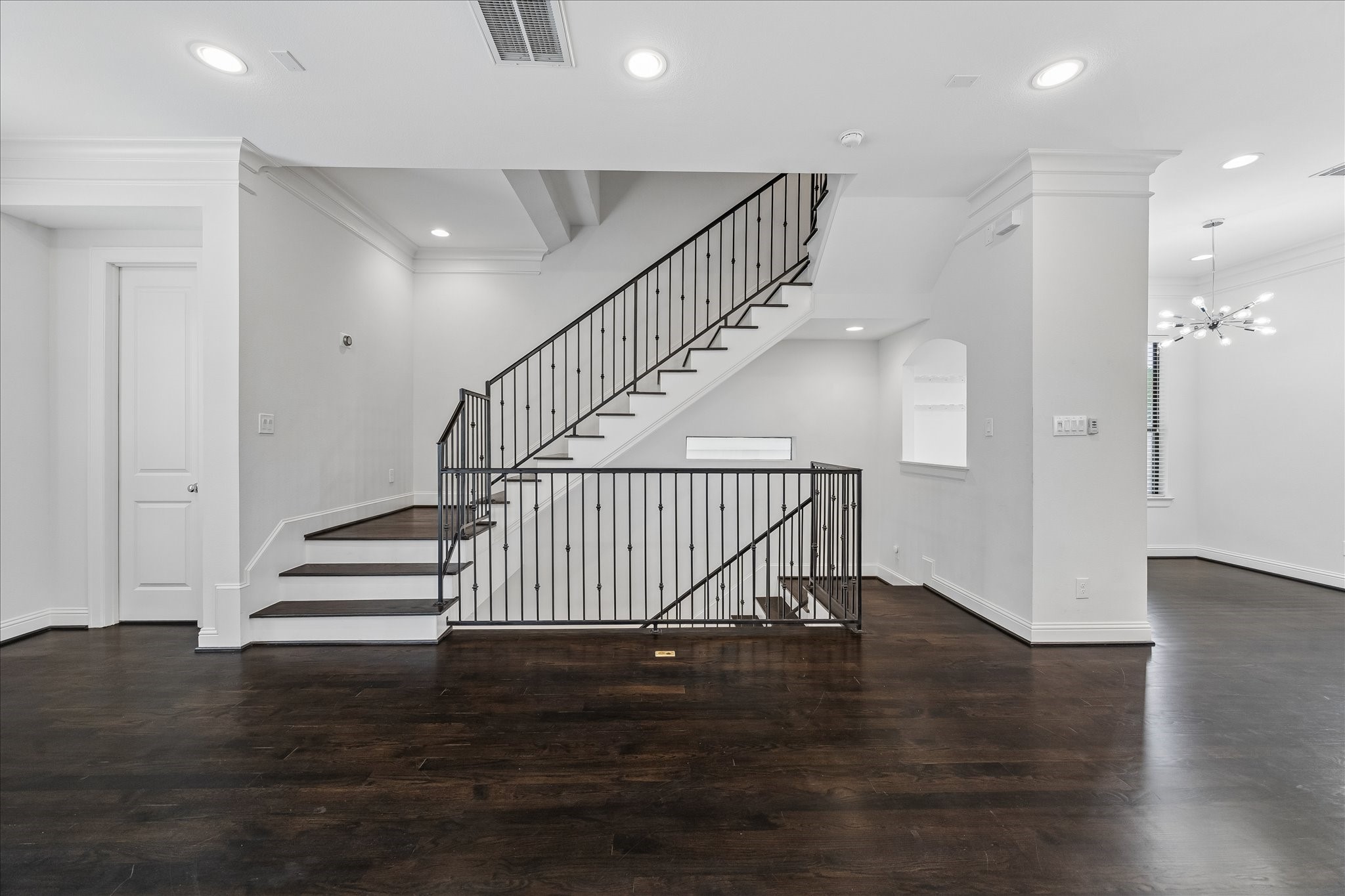 734 West 20th Street, Unit A Houston, TX 77008 - Photo 3 of 23 Open-concept living area w/ rich hardwood floors, high ceilings & abundant natural light, centered around a striking staircase w/ iron railing detail that adds architectural interest.