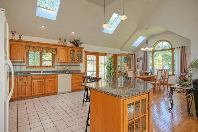 a kitchen with granite countertop a stove a sink dishwasher and a dining table with wooden floor