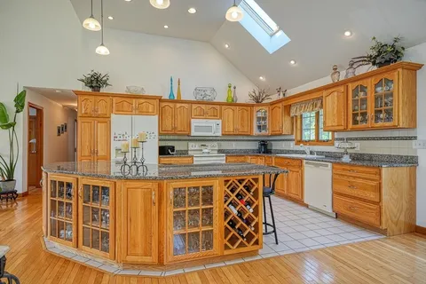 a kitchen with stainless steel appliances granite countertop a stove a sink dishwasher and a refrigerator with wooden floor